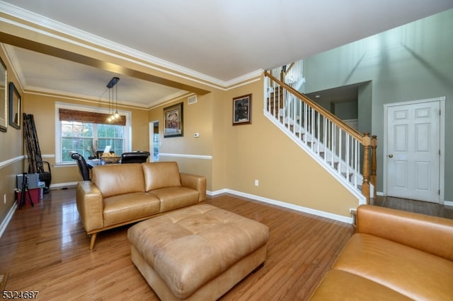 living room with ornamental molding, light hardwood / wood-style flooring, and a notable chandelier