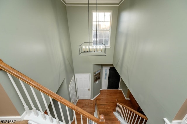 stairs featuring hardwood / wood-style flooring, a notable chandelier, and crown molding