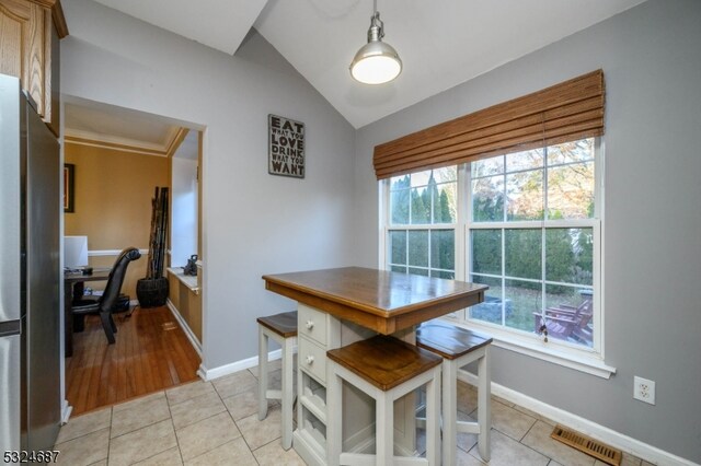 tiled dining space featuring plenty of natural light and vaulted ceiling