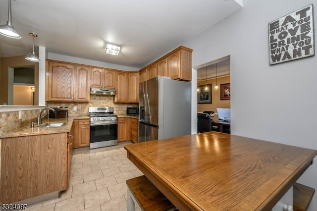 kitchen with sink, stainless steel appliances, light stone counters, backsplash, and decorative light fixtures