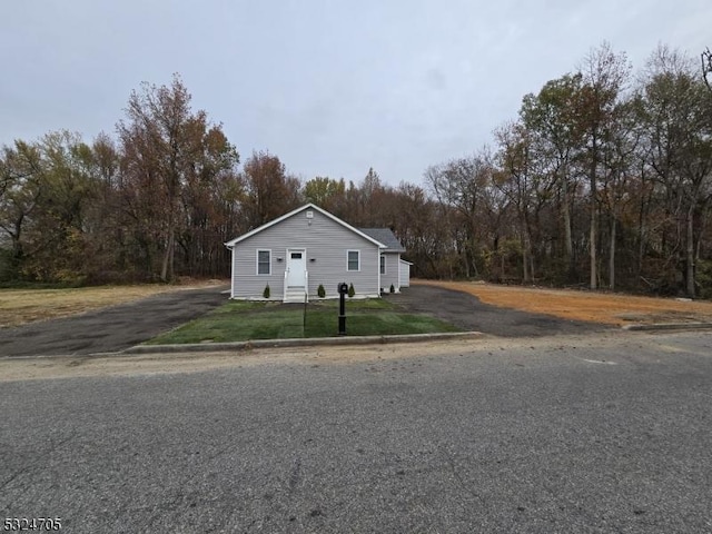 111 E Del A Vue Ave, Carneys Point Twp, NJ 08069 - view of side of home with asphalt driveway, a lawn, and a forest view