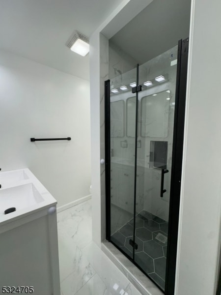 bathroom featuring a shower with door and vanity