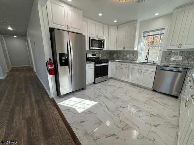 kitchen with stainless steel appliances, white cabinetry, tasteful backsplash, and sink