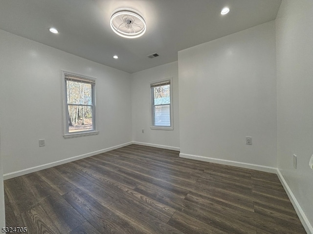 empty room featuring dark wood-type flooring and a healthy amount of sunlight