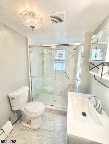 bathroom featuring vanity, toilet, baseboard heating, and a shower with shower door