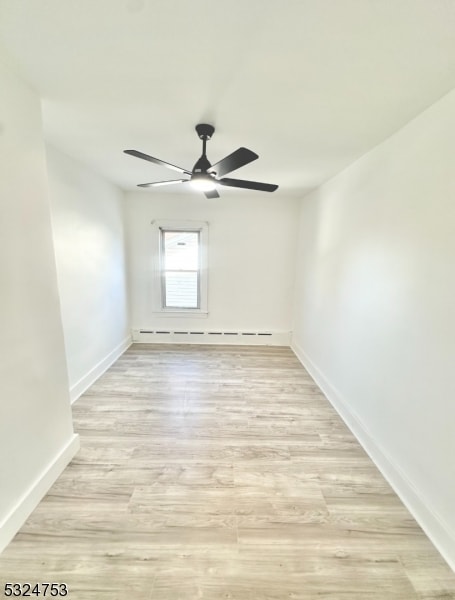 spare room with ceiling fan, light wood-type flooring, and baseboard heating