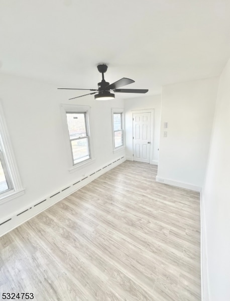 unfurnished room with light wood-type flooring, baseboard heating, and ceiling fan