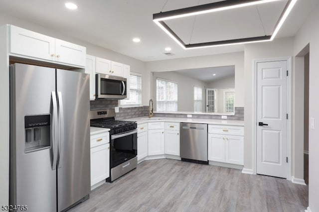 kitchen featuring sink, stainless steel appliances, light hardwood / wood-style flooring, decorative backsplash, and white cabinets