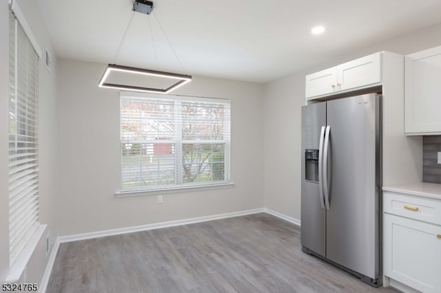 kitchen featuring white cabinets, stainless steel fridge, and light wood-type flooring