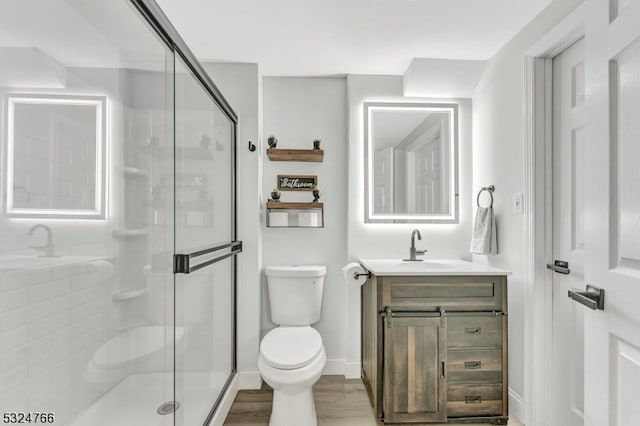 bathroom featuring vanity, hardwood / wood-style flooring, toilet, and walk in shower