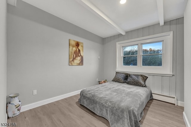 bedroom featuring beamed ceiling, light wood-type flooring, and a baseboard radiator