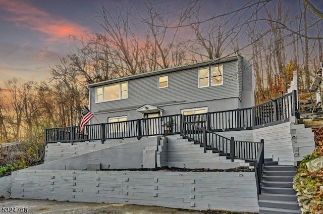 back house at dusk featuring a deck