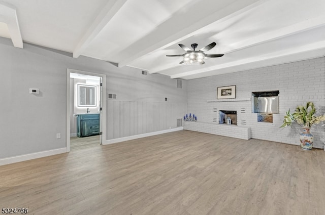 unfurnished living room with light wood-type flooring, a brick fireplace, brick wall, ceiling fan, and beamed ceiling