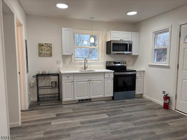 kitchen featuring decorative light fixtures, white cabinetry, sink, and appliances with stainless steel finishes