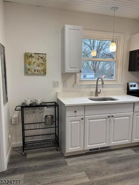 kitchen featuring white cabinetry, dark wood-type flooring, sink, and hanging light fixtures