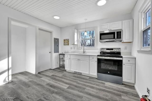 kitchen with sink, pendant lighting, stainless steel appliances, light hardwood / wood-style floors, and white cabinets