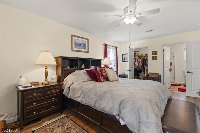 bedroom featuring hardwood / wood-style floors, a walk in closet, a closet, and ceiling fan