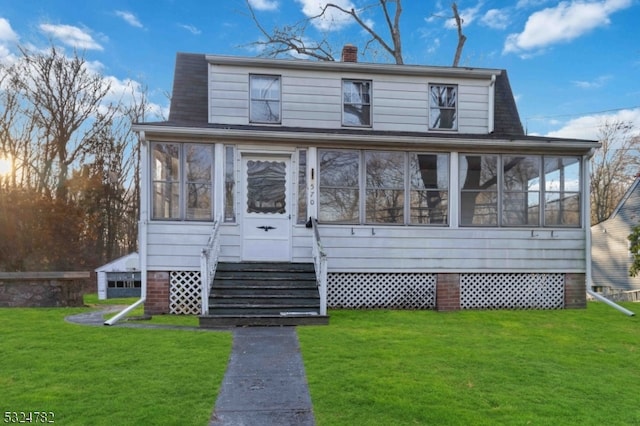 view of front of home with a sunroom and a front lawn