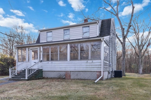 view of front of house with a front yard, central air condition unit, and a sunroom