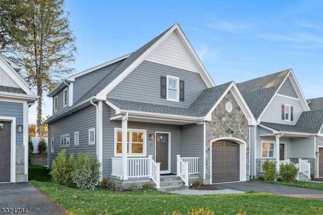 view of front of property featuring a porch, a garage, and a front lawn