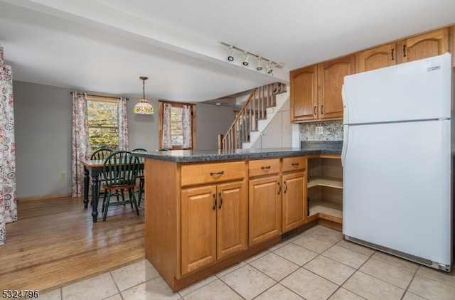 kitchen with kitchen peninsula, light tile patterned floors, white refrigerator, and hanging light fixtures