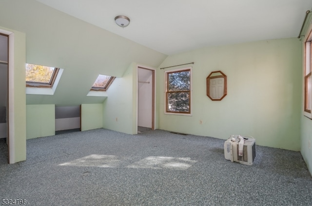 additional living space featuring carpet flooring and vaulted ceiling with skylight