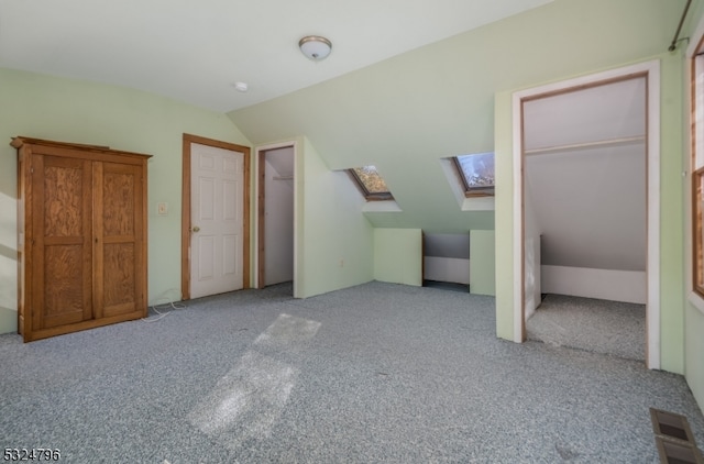 unfurnished bedroom with vaulted ceiling with skylight and light carpet