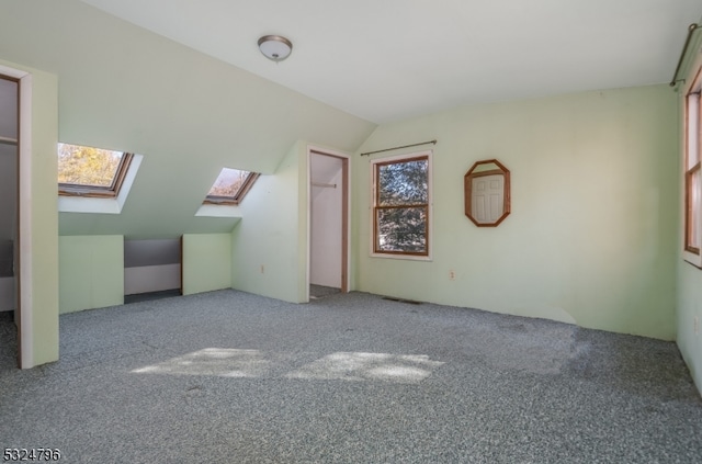 additional living space featuring vaulted ceiling with skylight and carpet flooring