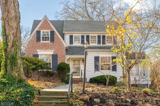 view of front of house with brick siding and roof with shingles