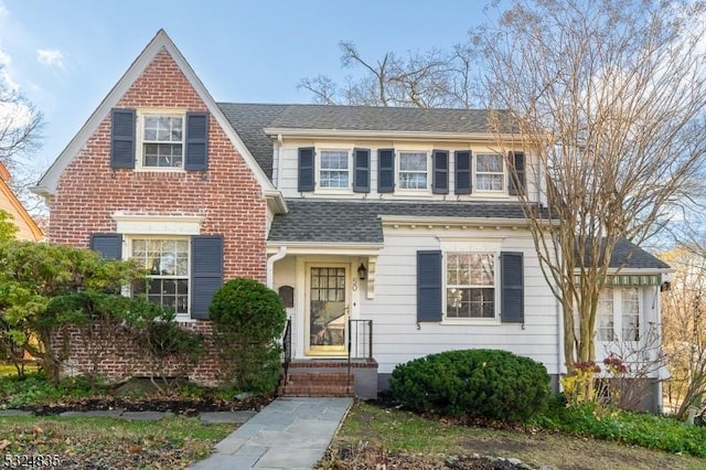 view of front of house with a shingled roof and brick siding