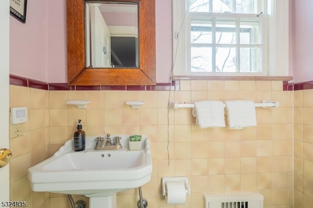 bathroom with a sink, tile walls, and radiator