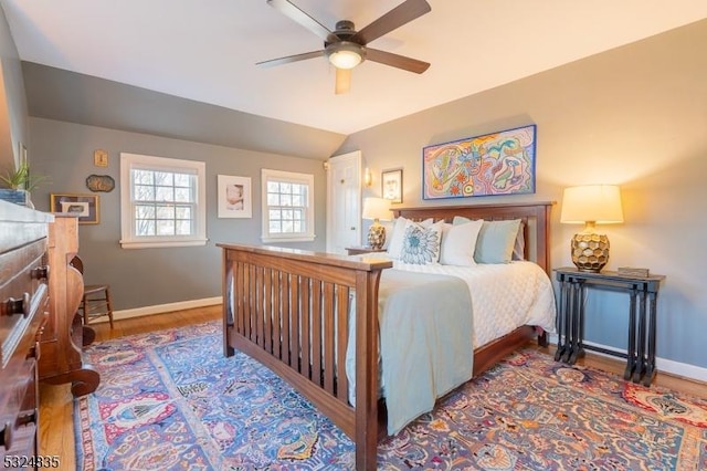 bedroom with a ceiling fan, vaulted ceiling, baseboards, and wood finished floors