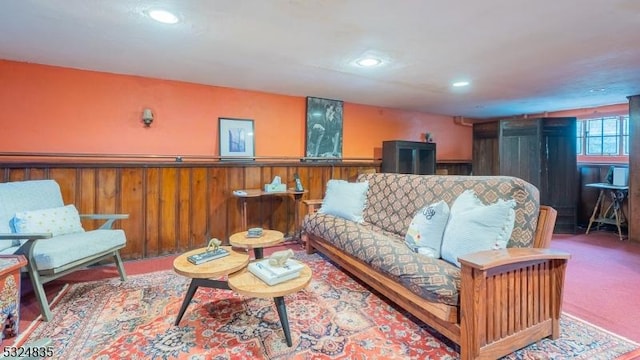 living area with wood walls, recessed lighting, light colored carpet, and wainscoting