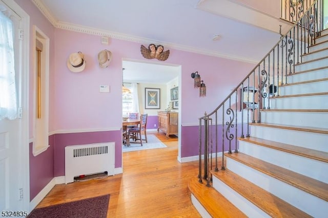 foyer featuring stairway, radiator heating unit, wood finished floors, and crown molding