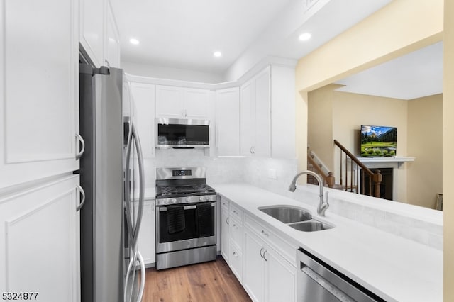 kitchen with white cabinetry, sink, stainless steel appliances, dark hardwood / wood-style flooring, and backsplash