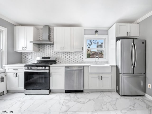 kitchen with sink, wall chimney range hood, appliances with stainless steel finishes, white cabinets, and ornamental molding