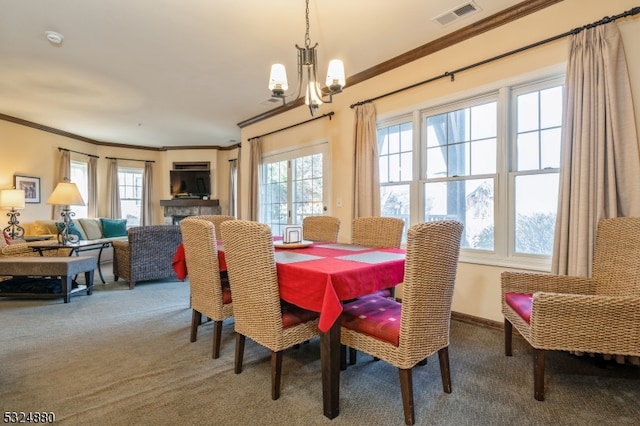 carpeted dining room with ornamental molding, an inviting chandelier, and a healthy amount of sunlight