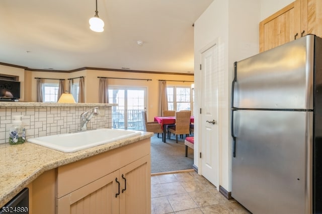 kitchen with stainless steel fridge, light brown cabinetry, crown molding, sink, and decorative light fixtures