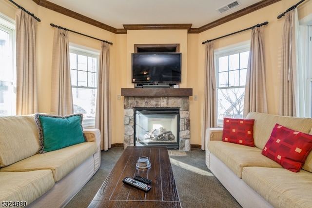 living room with a stone fireplace, a wealth of natural light, crown molding, and carpet floors