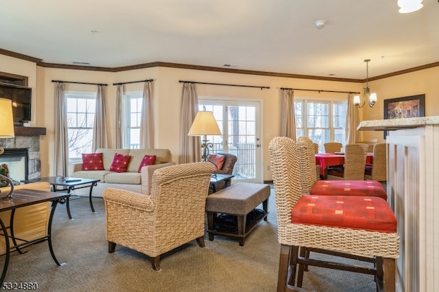 living room with a chandelier, carpet floors, a stone fireplace, and crown molding