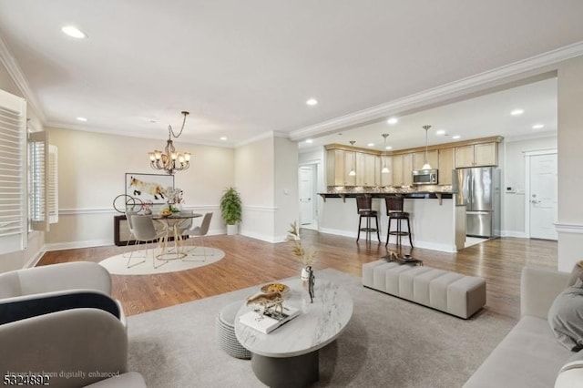 living area featuring ornamental molding, an inviting chandelier, wood finished floors, and recessed lighting