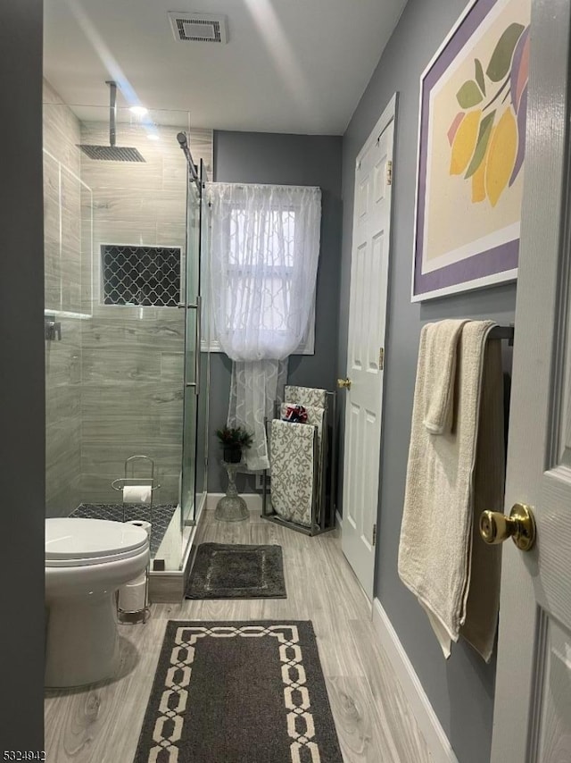 bathroom with a shower with door, wood-type flooring, and toilet