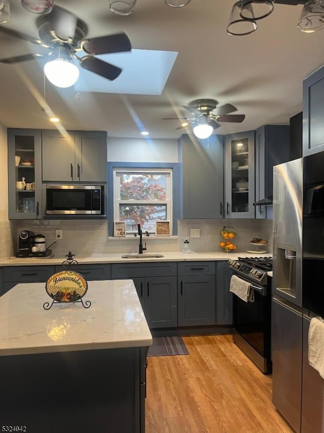 kitchen with light stone counters, sink, light hardwood / wood-style flooring, and stainless steel appliances