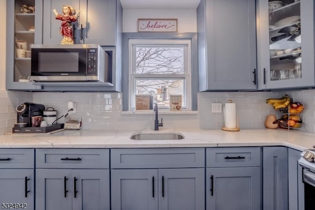 kitchen with gray cabinets, sink, and light stone countertops