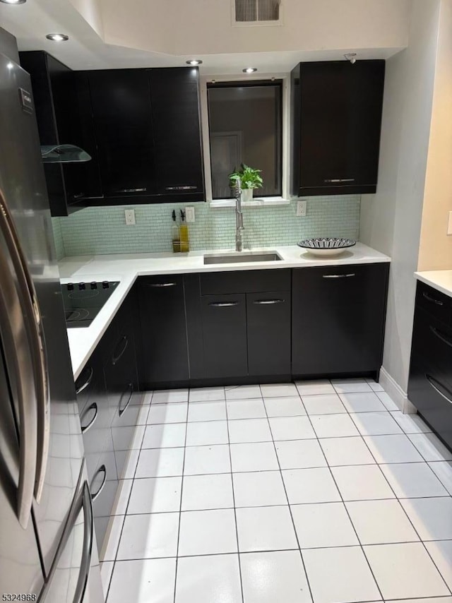 kitchen featuring stainless steel refrigerator, sink, tasteful backsplash, black electric stovetop, and light tile patterned floors