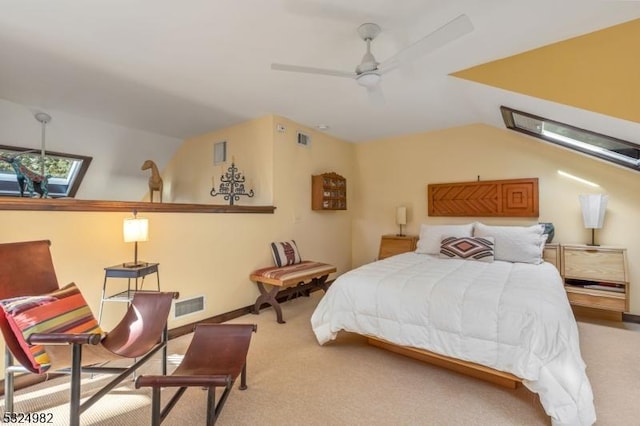 carpeted bedroom with ceiling fan and vaulted ceiling with skylight