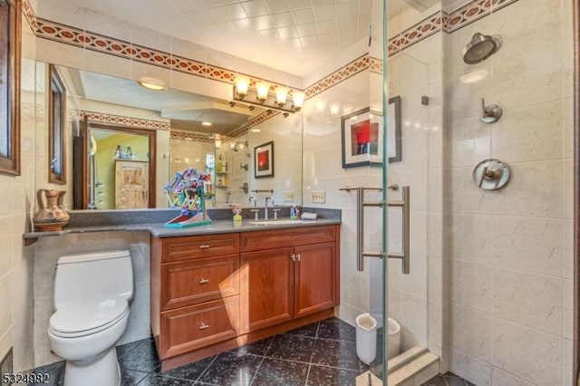 bathroom featuring vanity, a shower with door, toilet, and tile walls