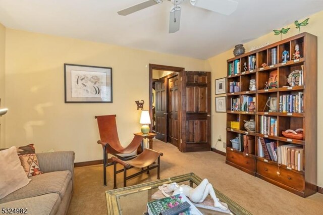 sitting room with ceiling fan and light colored carpet