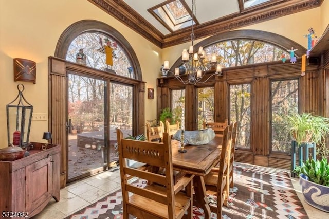 dining room with a healthy amount of sunlight, ornamental molding, a high ceiling, and an inviting chandelier