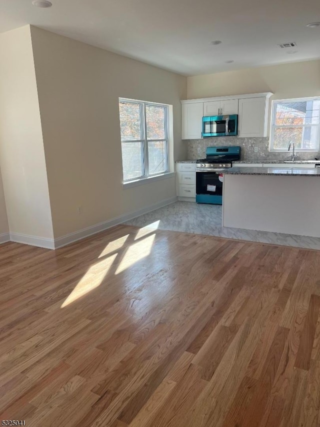 kitchen with white cabinets, appliances with stainless steel finishes, light hardwood / wood-style flooring, and plenty of natural light